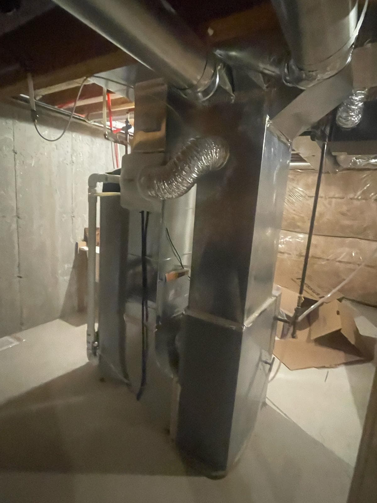 Rectangular duct trunk and flexible duct beside a furnace in a basement
