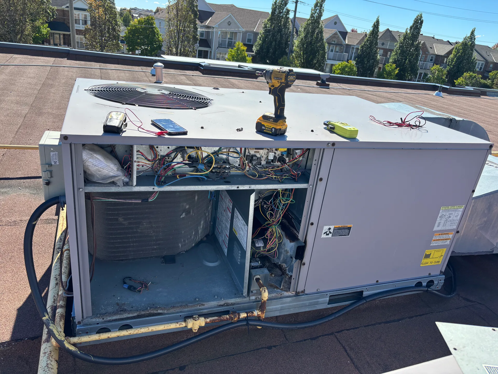 Rooftop HVAC unit with the cabinet open during service, fan and coil visible